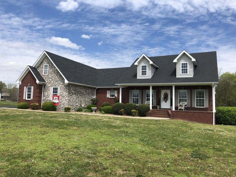 An elegant brick and stone home with newly installed black shingles
