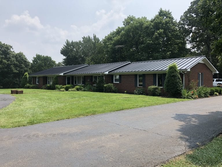 Brick home with elegant black standing seam roofing